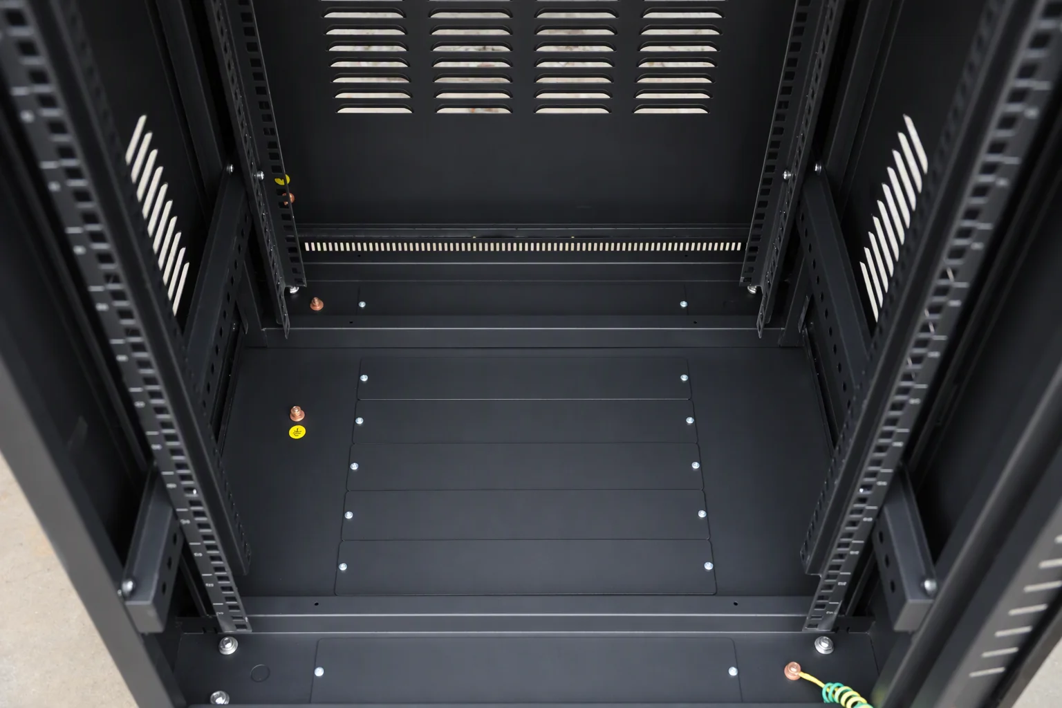 Empty 42U rack interior photographed from above: mounting beams, rails, U-position markings and a grounding stud, with no equipment and no branding in the frame